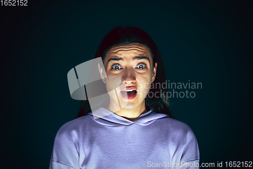 Image of Close up portrait of young crazy scared and shocked woman isolated on dark background