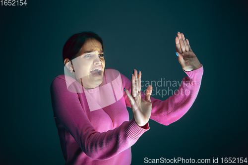 Image of Close up portrait of young crazy scared and shocked woman isolated on dark background