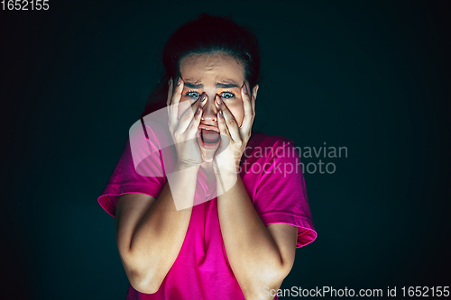 Image of Close up portrait of young crazy scared and shocked woman isolated on dark background