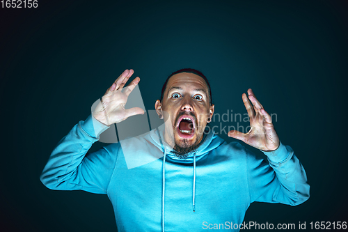 Image of Close up portrait of young crazy scared and shocked man isolated on dark background