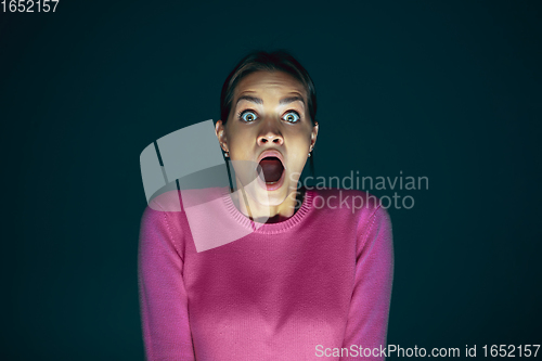 Image of Close up portrait of young crazy scared and shocked woman isolated on dark background