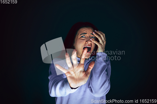 Image of Close up portrait of young crazy scared and shocked woman isolated on dark background