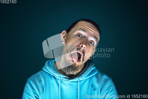 Image of Close up portrait of young crazy scared and shocked man isolated on dark background