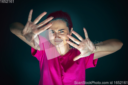 Image of Close up portrait of young crazy scared and shocked woman isolated on dark background