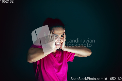 Image of Close up portrait of young crazy scared and shocked woman isolated on dark background