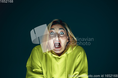 Image of Close up portrait of young crazy scared and shocked woman isolated on dark background