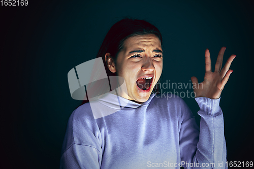 Image of Close up portrait of young crazy scared and shocked woman isolated on dark background