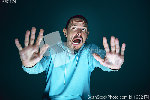 Image of Close up portrait of young crazy scared and shocked man isolated on dark background