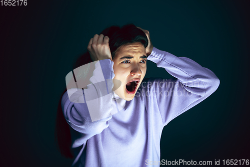 Image of Close up portrait of young crazy scared and shocked woman isolated on dark background