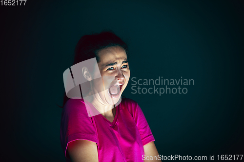 Image of Close up portrait of young crazy scared and shocked woman isolated on dark background