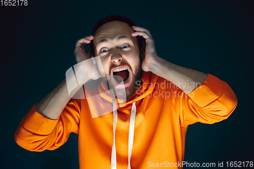 Image of Close up portrait of crazy scared and shocked man isolated on dark background