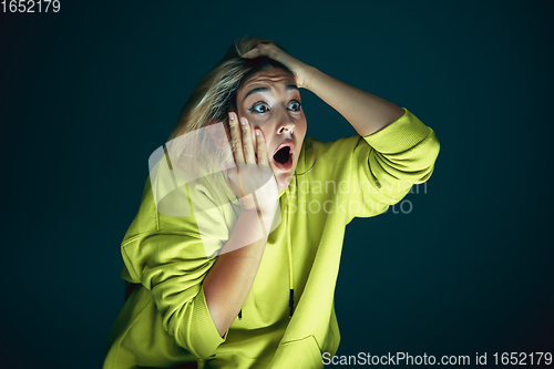 Image of Close up portrait of young crazy scared and shocked woman isolated on dark background