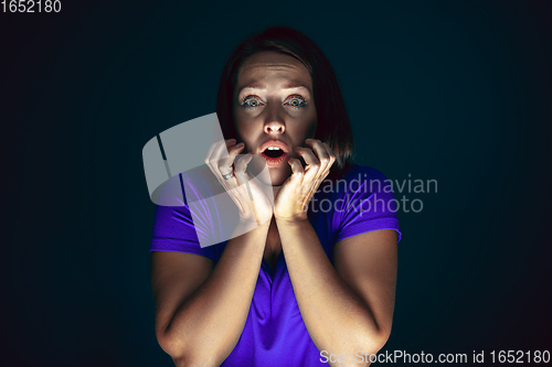 Image of Close up portrait of young crazy scared and shocked woman isolated on dark background