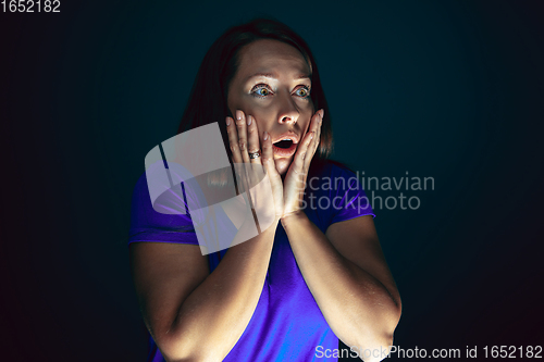 Image of Close up portrait of young crazy scared and shocked woman isolated on dark background