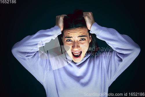 Image of Close up portrait of young crazy scared and shocked woman isolated on dark background