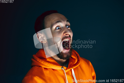 Image of Close up portrait of crazy scared and shocked man isolated on dark background