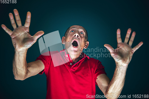 Image of Close up portrait of crazy scared and shocked man isolated on dark background