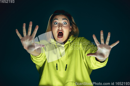 Image of Close up portrait of young crazy scared and shocked woman isolated on dark background