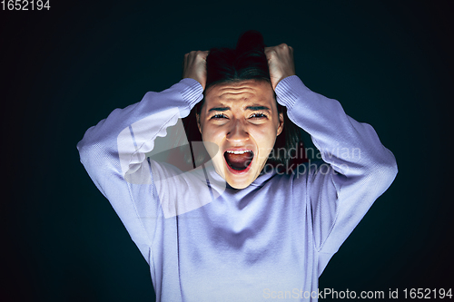 Image of Close up portrait of young crazy scared and shocked woman isolated on dark background