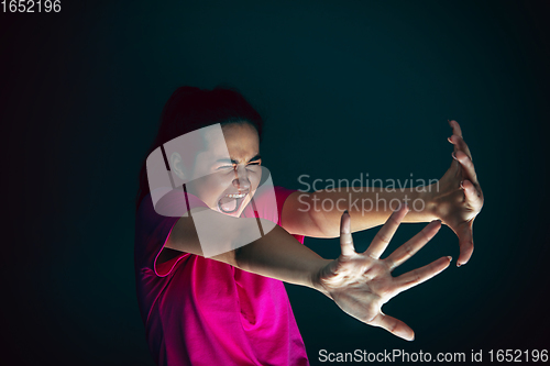 Image of Close up portrait of young crazy scared and shocked woman isolated on dark background