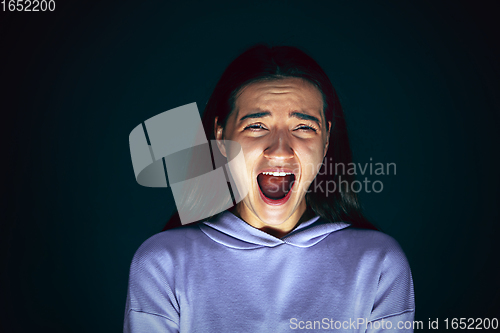 Image of Close up portrait of young crazy scared and shocked woman isolated on dark background