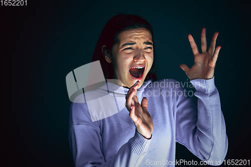 Image of Close up portrait of young crazy scared and shocked woman isolated on dark background