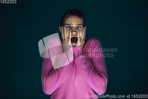 Image of Close up portrait of young crazy scared and shocked woman isolated on dark background