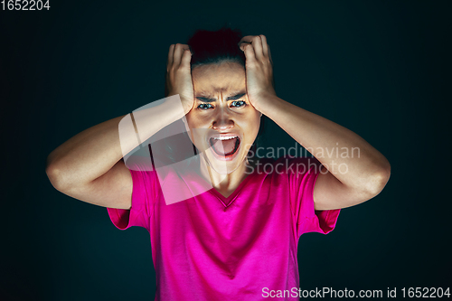 Image of Close up portrait of young crazy scared and shocked woman isolated on dark background