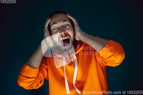 Image of Close up portrait of crazy scared and shocked man isolated on dark background