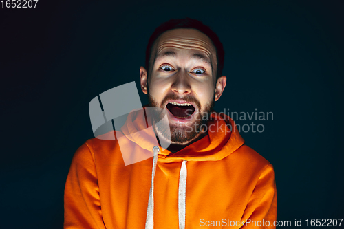 Image of Close up portrait of crazy scared and shocked man isolated on dark background