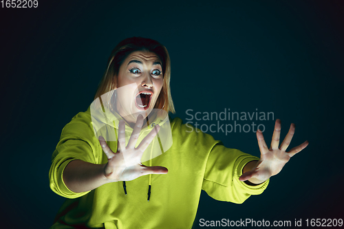 Image of Close up portrait of young crazy scared and shocked woman isolated on dark background