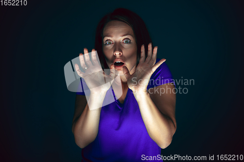 Image of Close up portrait of young crazy scared and shocked woman isolated on dark background