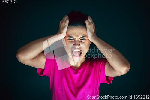 Image of Close up portrait of young crazy scared and shocked woman isolated on dark background