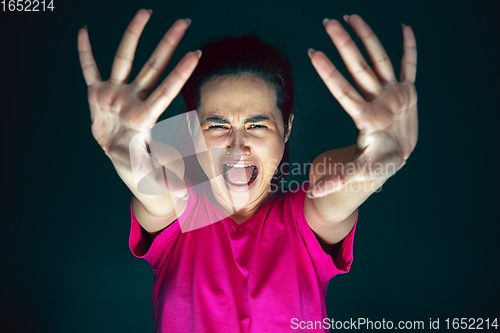 Image of Close up portrait of young crazy scared and shocked woman isolated on dark background