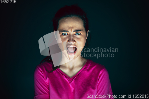 Image of Close up portrait of young crazy scared and shocked woman isolated on dark background