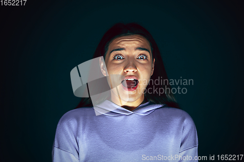 Image of Close up portrait of young crazy scared and shocked woman isolated on dark background