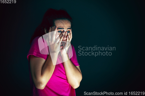 Image of Close up portrait of young crazy scared and shocked woman isolated on dark background