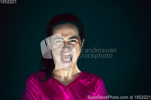 Image of Close up portrait of young crazy scared and shocked woman isolated on dark background