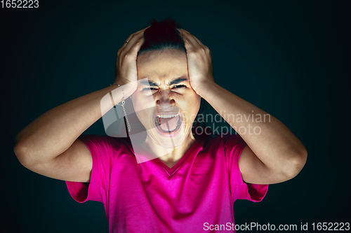 Image of Close up portrait of young crazy scared and shocked woman isolated on dark background