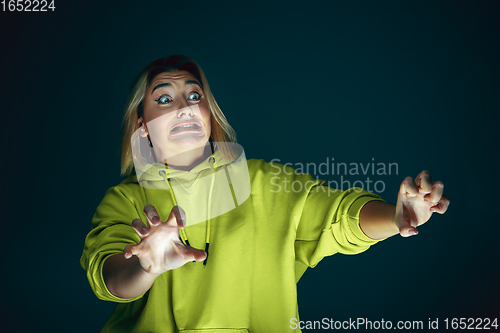 Image of Close up portrait of young crazy scared and shocked woman isolated on dark background