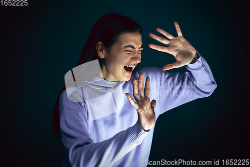 Image of Close up portrait of young crazy scared and shocked woman isolated on dark background