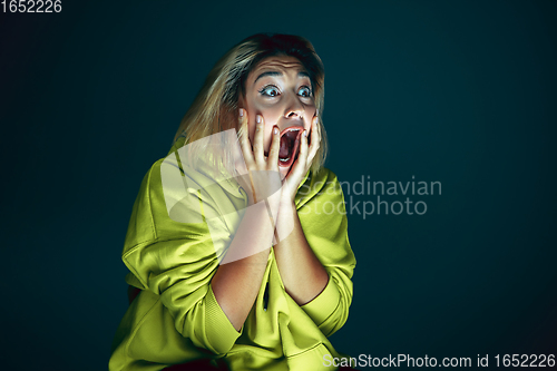 Image of Close up portrait of young crazy scared and shocked woman isolated on dark background