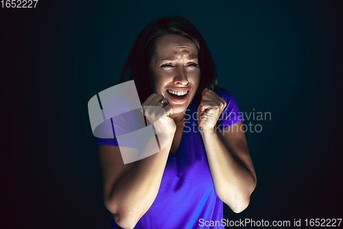 Image of Close up portrait of young crazy scared and shocked woman isolated on dark background