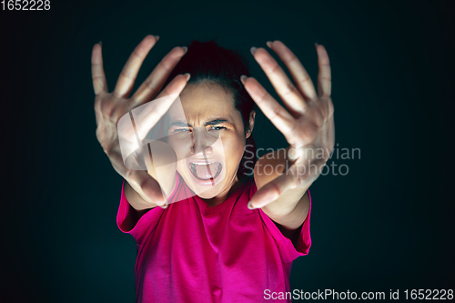 Image of Close up portrait of young crazy scared and shocked woman isolated on dark background