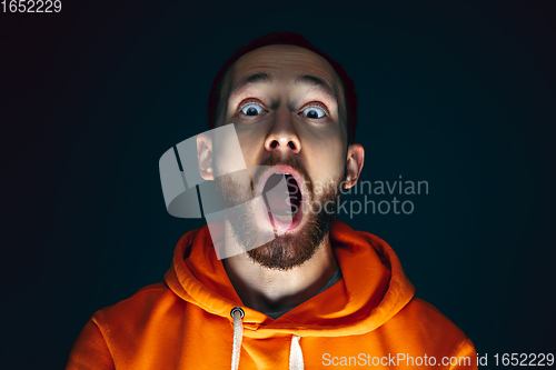 Image of Close up portrait of crazy scared and shocked man isolated on dark background