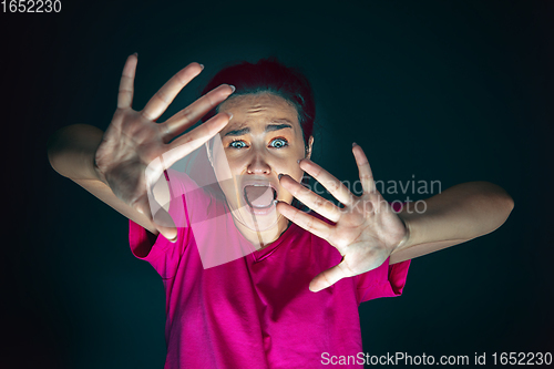 Image of Close up portrait of young crazy scared and shocked woman isolated on dark background