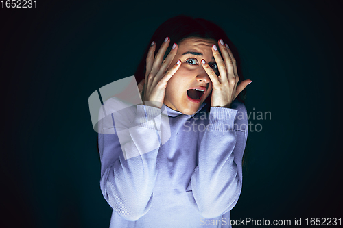 Image of Close up portrait of young crazy scared and shocked woman isolated on dark background