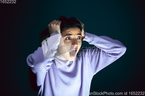 Image of Close up portrait of young crazy scared and shocked woman isolated on dark background