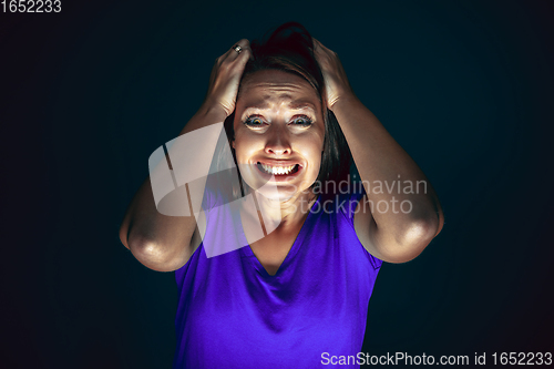 Image of Close up portrait of young crazy scared and shocked woman isolated on dark background