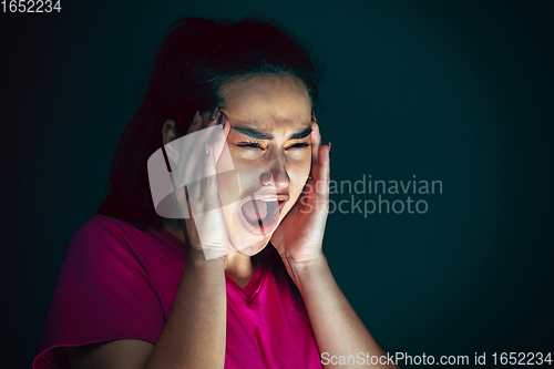 Image of Close up portrait of young crazy scared and shocked woman isolated on dark background